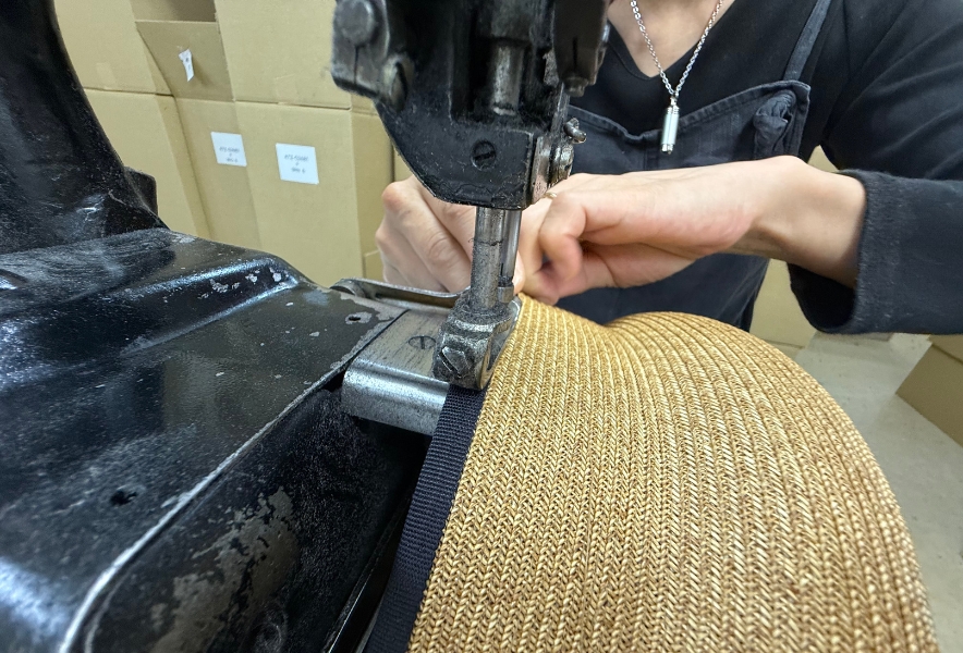 環縫いミシンでブレードを縫い合わせる帽子職人の手元。名古屋市熱田区の工房での制作風景。